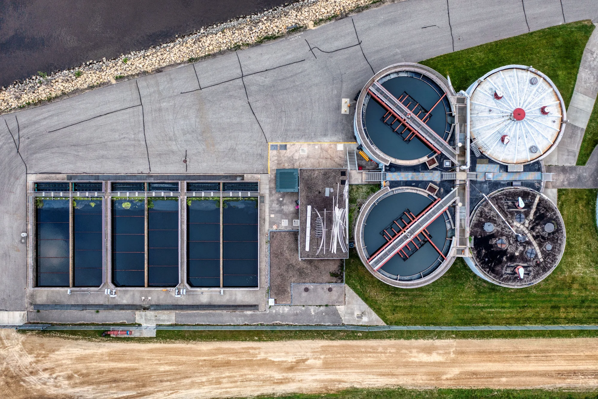 Aerial view of municipal water-treatment infrastructure with circular and rectangular treatment basins