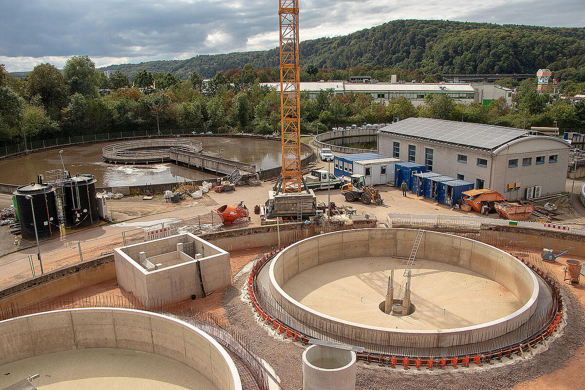 Water-treatment facility under construction with circular concrete basins and site crane